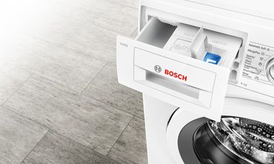 Das Bild zeigt eine moderne Waschmaschine in weiß, die im Einsatz ist. Das Gerät hat eine Tür, durch die das Innere sichtbar ist, und befindet sich in einer hellen, sauberen Umgebung.